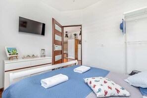 A bedroom with a bed, a TV, a dresser, and a mirror.