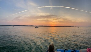 A calm body of water with boats and a sunset in the distance. - Clam Lake Waterfront Cottage (Bellaire)