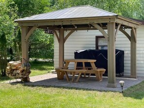 A wooden gazebo with a picnic table, surrounded by a brick patio and a covered grill area. - Clam Lake Waterfront Cottage (Bellaire)