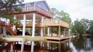 Ein Haus mit einer Terrasse, die auf Säulen über dem Wasser gebaut ist.