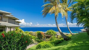 A coastal property with a view of the ocean, a palm tree, and a house with a balcony. - Ridge 1712- Ocean View w/Platinum Interiors! (Lahaina)
