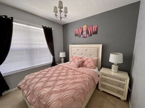 A bedroom with a bed, nightstands, a chandelier, and a window with curtains. - Disney Villa| Private Pool|5 mins to Disney|Resort amenities (Kissimmee)