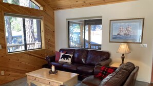 A cozy cabin interior with a leather sofa, a wooden coffee table, and a lamp. - Preferred Parking Pass to Dodge Ridge (Cold Springs)