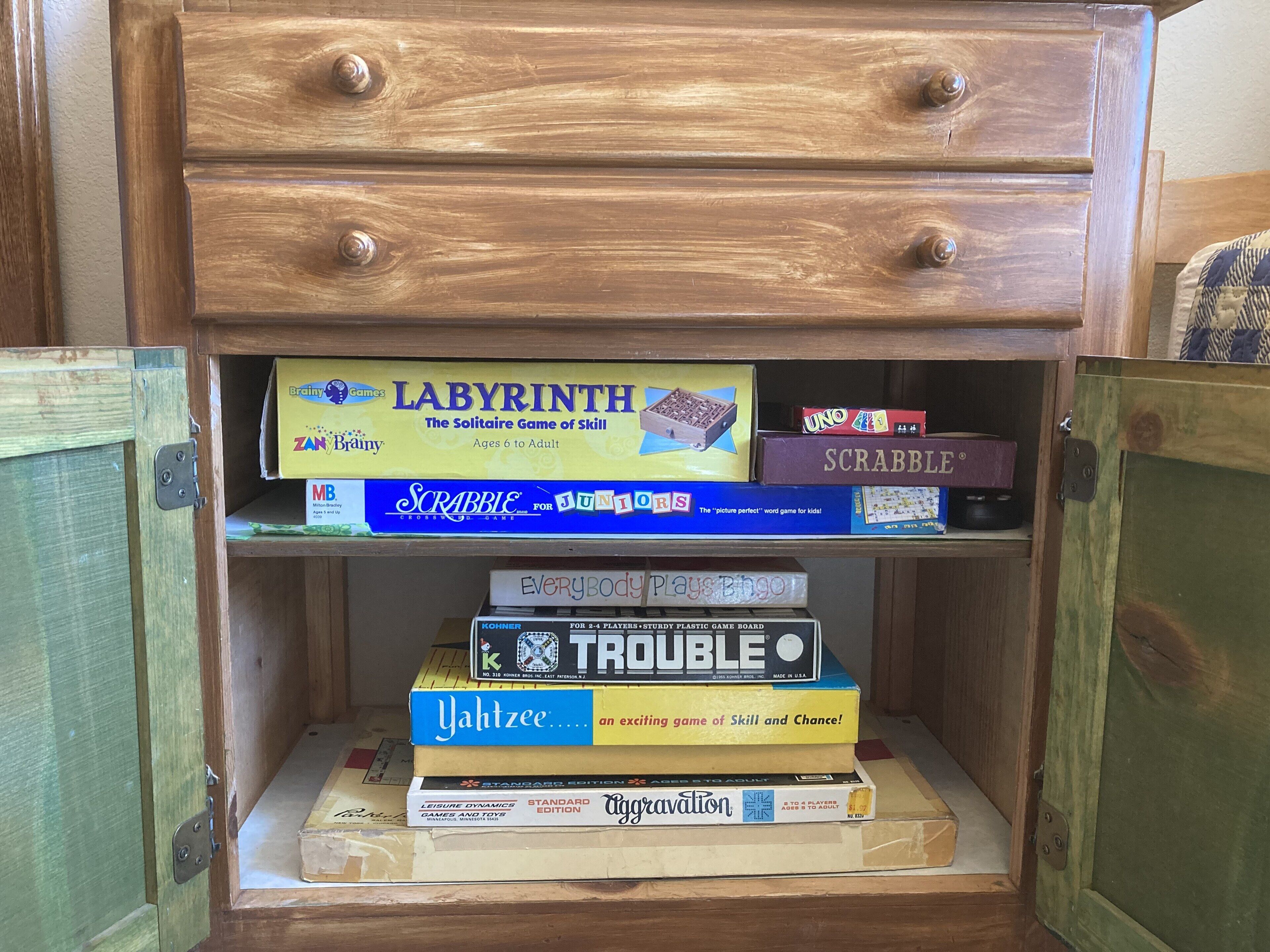 Et træskab med flere hylder fyldt med diverse brætspil.