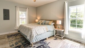 A bedroom with a bed, nightstands, a ceiling fan, and a window with curtains.