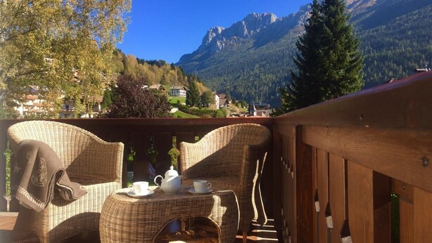 A balcony with wicker furniture and a table, overlooking a mountainous landscape. - Apartment "Residence Lastè Catinaccio" with Mountain View, Wi-Fi, Garden & Balcony (Moena)