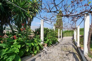 A garden pathway with white columns, lush greenery, and a view of the landscape. - Holiday Home 'Can Moragues' with Mountain View, Wi-Fi and Air Conditioning (Pollensa)