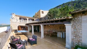 A stone building with a patio area, outdoor seating, and a table. - Holiday Home 'Can Moragues' with Mountain View, Wi-Fi and Air Conditioning (Pollensa)