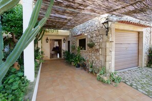 A covered outdoor area with a stone wall, a wooden door, and potted plants. - Holiday Home 'Can Moragues' with Mountain View, Wi-Fi and Air Conditioning (Pollensa)