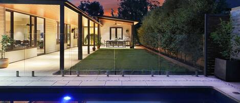 Enjoy a serene outdoor space with a pool, dining area, and covered kitchen.