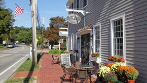 Un escaparate con un letrero que dice 'Barnstable Market' y asientos al aire libre con sillas y mesas.