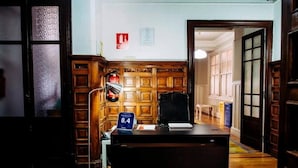 A reception desk with a sign indicating room number 8.4, a fire extinguisher, and a telephone. - Zentric Hostel (León)