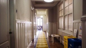 A hallway with a patterned carpet, a bench, and storage boxes. - Zentric Hostel (León)