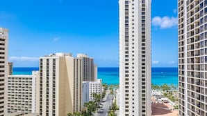 A high-rise hotel with multiple floors, a view of the ocean, and a clear sky.