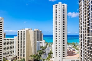 A high-rise hotel with multiple floors, a view of the ocean, and a clear sky.