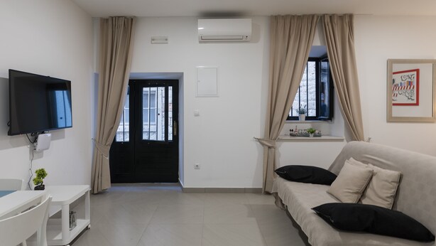 A modern living room with a sofa, TV, and a door leading outside. - Apartment Navigator (Dubrovnik)