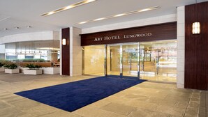 L’entrée d’un hôtel, avec un tapis bleu, une façade en bois et une porte en verre.