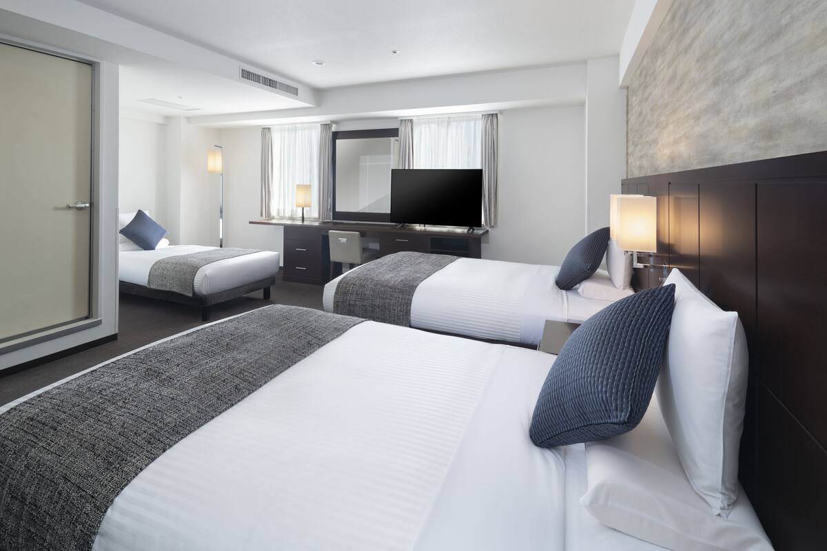 Une chambre d’hôtel avec deux lits, un bureau, un téléviseur à écran plat et un grand miroir.