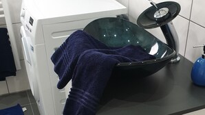 A laundry area with a washing machine, a drying rack, and a sink with a blue basin. - Air-conditioned apartment 2, great connection to Vienna + super-fast WLAN (Neulengbach)