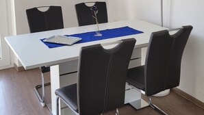 A modern dining area with a white table, black chairs, a blue placemat, and a large blue painting on the wall. - Air-conditioned apartment 2, great connection to Vienna + super-fast WLAN (Neulengbach)