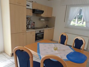 Eine kompakte Küche mit Holzausstattung, einem eingebauten Backofen und einem Fenster mit Vorhängen.