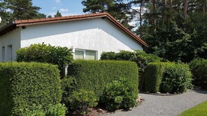 A modern house with a white exterior, a gravel driveway, and neatly trimmed hedges. - Lenz Süd Fw 1 - Holiday apartment 1 - 68027 (Fünfseen)