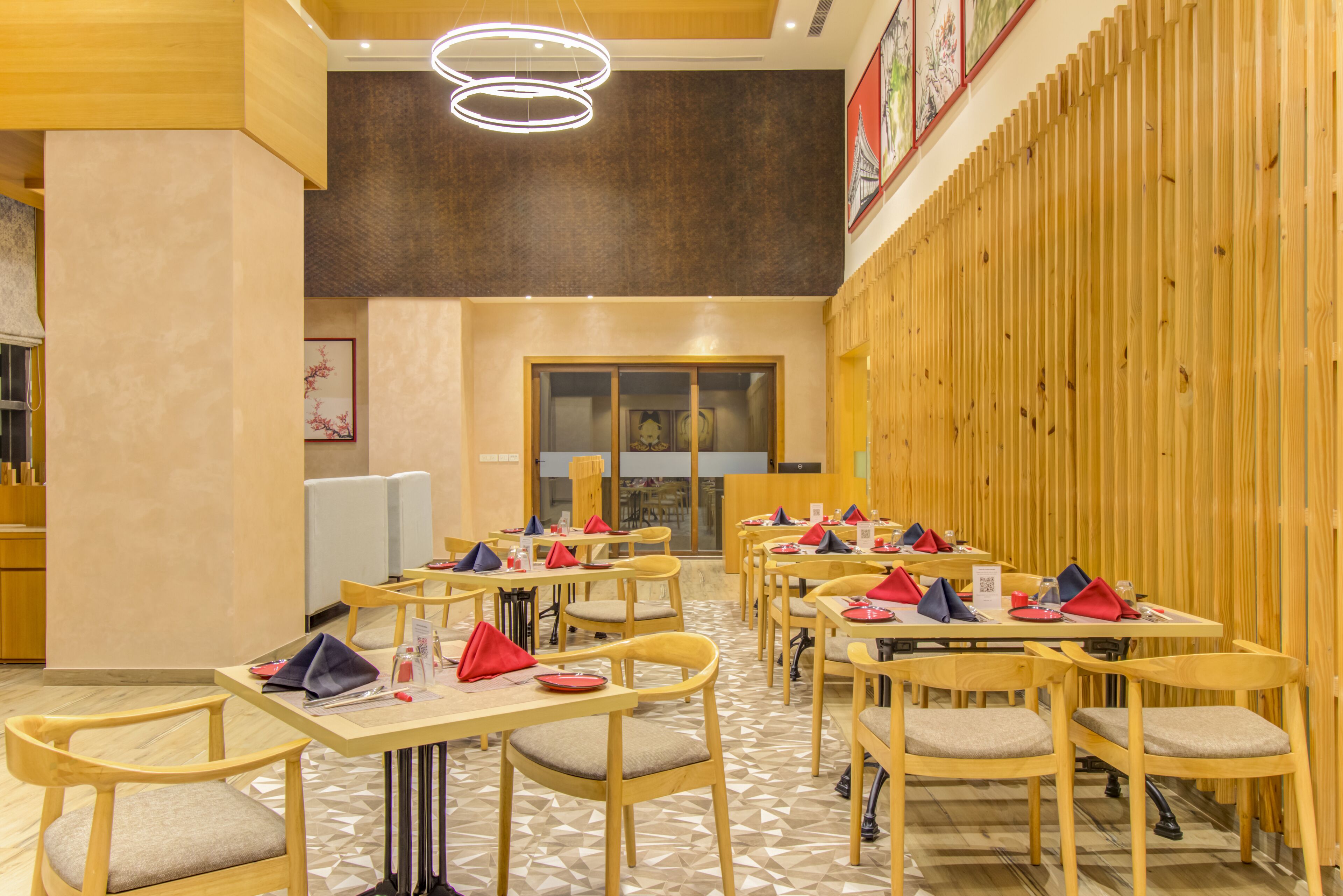 A restaurant with multiple tables and chairs, wooden walls, and a geometric patterned floor.