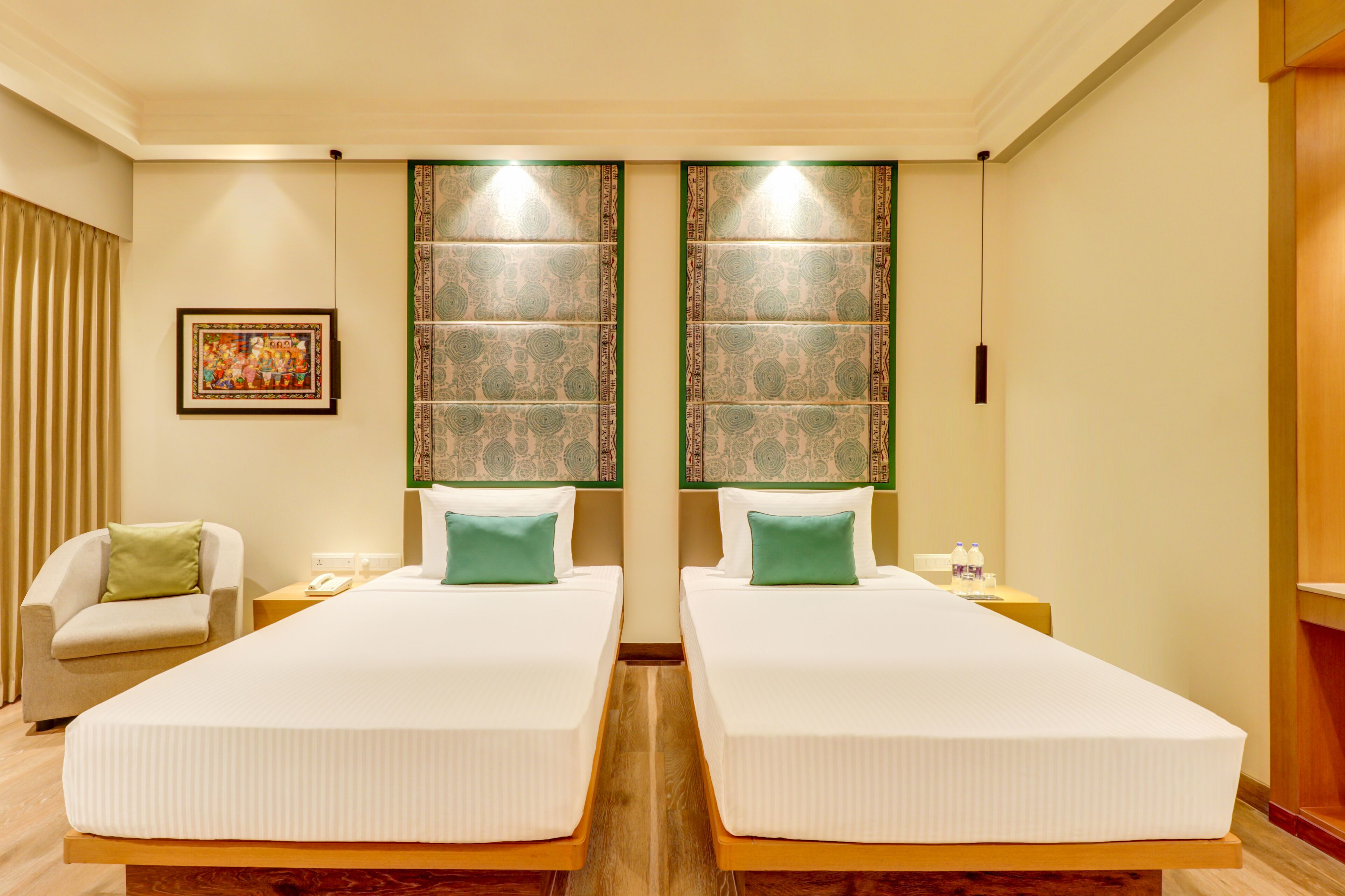 Habitación de hotel con dos camas individuales, una silla, una mesita de noche, un teléfono y un panel decorativo en la pared.