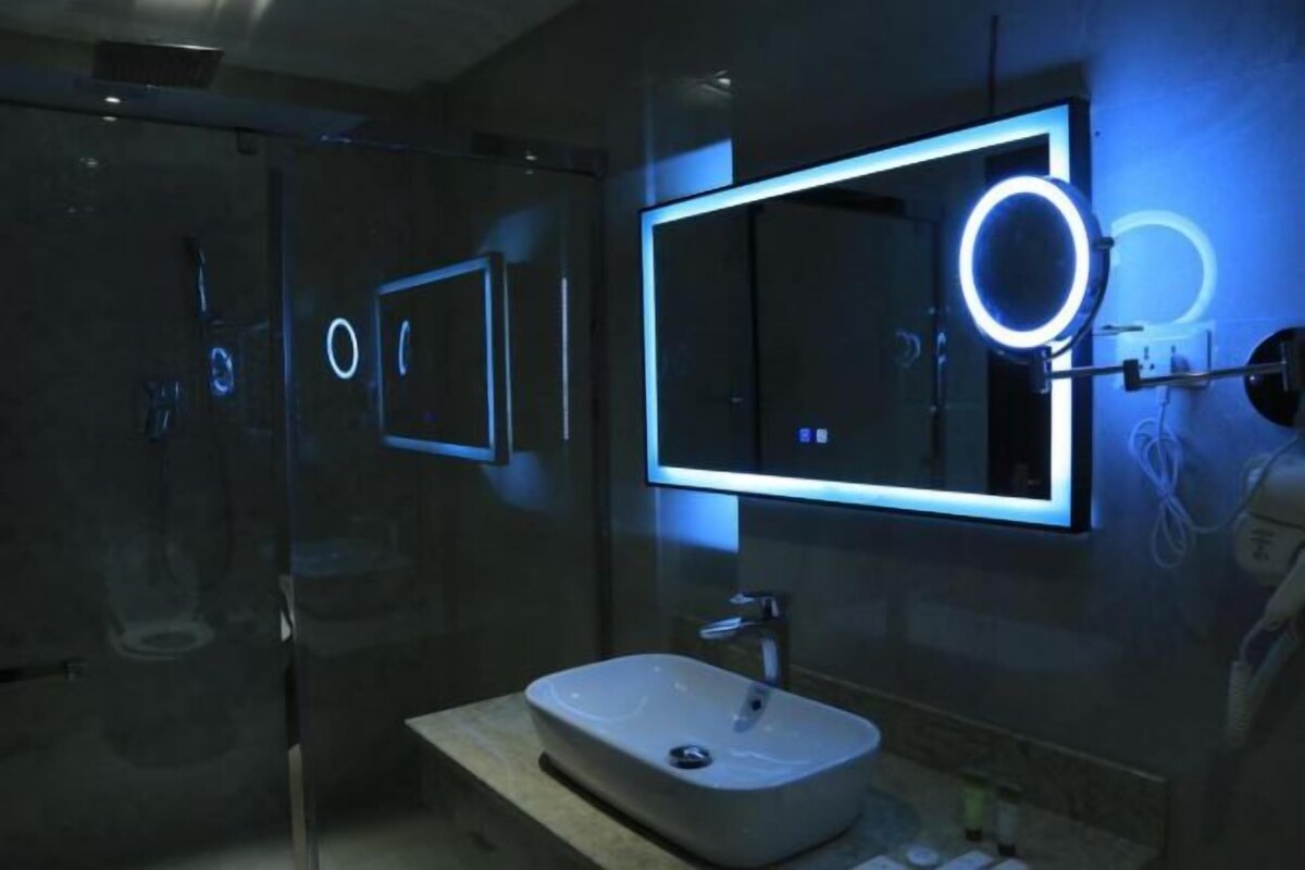 Ein modernes Badezimmer mit einem großen Spiegel, einem Waschbecken und einer Duschkabine aus Glas.