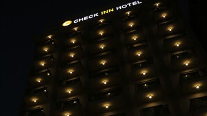 Un bâtiment sur lequel on peut lire, en haut, une enseigne indiquant « CHECK INN HOTEL ».