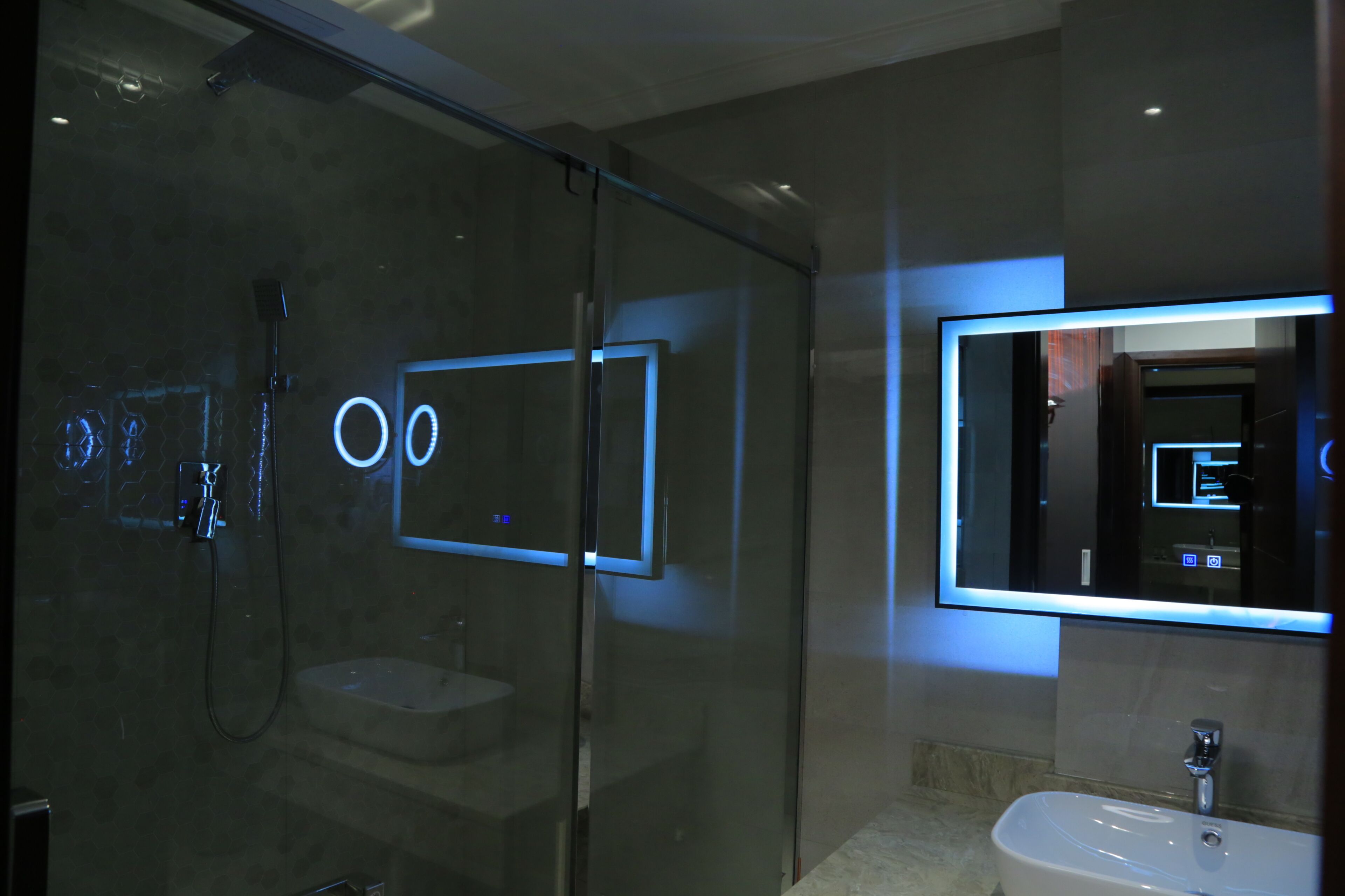 Une salle de bain moderne dotée d’une douche à parois de verre, d’un lavabo indépendant et d’un miroir avec éclairage intégré.
