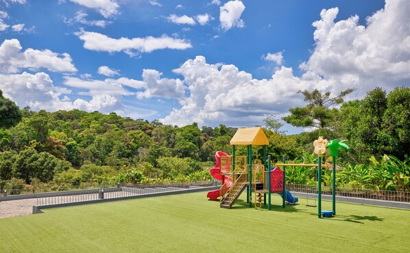 A playground with slides and climbing structures, surrounded by lush greenery and a clear sky. - Gateway Coorg (Madikeri)
