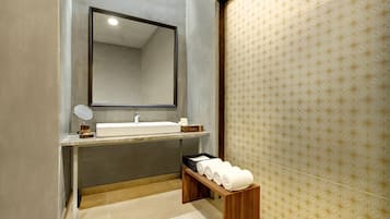Un baño moderno con un espejo grande, un lavabo y un banco de madera con toallas.