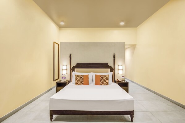 Una habitación de hotel con una cama grande, dos mesitas de noche y un cabecero.