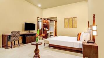 A hotel room with a bed, desk, chair, TV, and a small table with a plant.