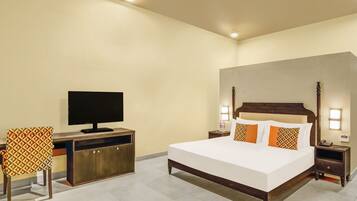A hotel room with a large bed, a TV on a wooden cabinet, a desk with a chair, and bedside lamps.