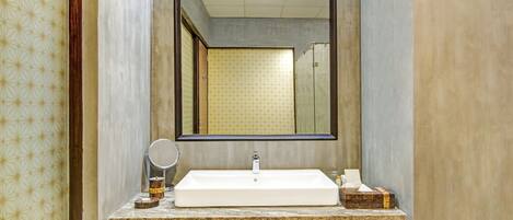 Un baño con un espejo grande, un lavabo blanco y una estantería con toallas ordenadamente dobladas.