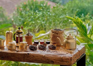 A rustic wooden table with coffee brewing equipment and a burlap sack labeled "COFFEE" in a garden setting. - Gateway Coorg (Madikeri)