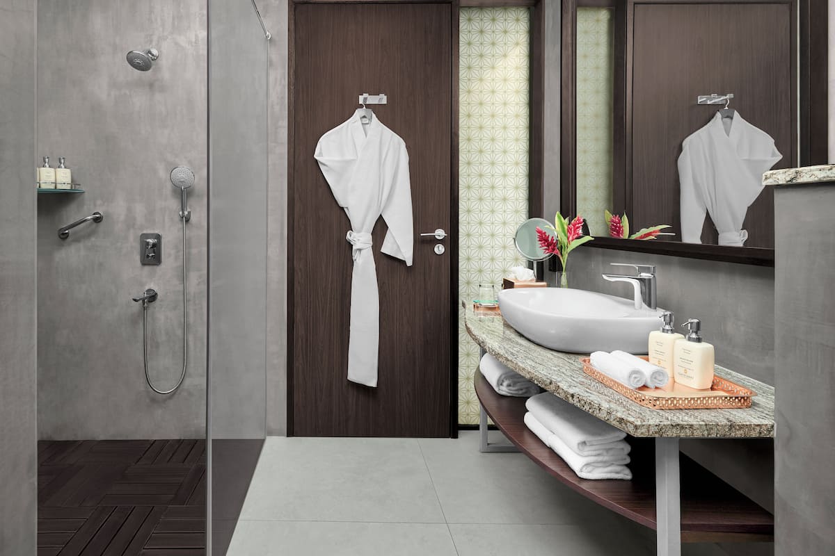 A modern bathroom with a shower, a sink with a marble countertop, and a wooden door.
