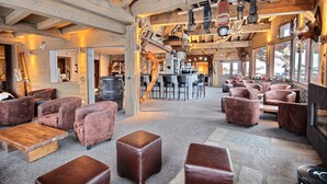 Een ruime lobby met leren banken, houten tafels en een bar.