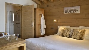 Een kamer met houten lambrisering, een bed, een houten kledingkast, een witte handdoek en een afbeelding van een ijsbeer aan de muur.