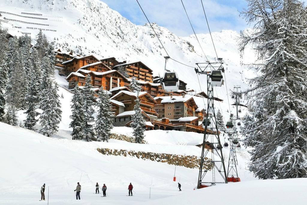 A ski resort with wooden lodges, a ski lift, and snow-covered trees.