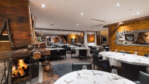 Een restaurant met meerdere tafels, een open haard en een rustieke inrichting.
