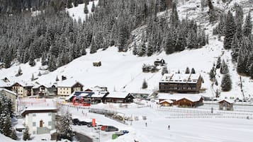 A snow-covered ski resort with buildings, a ski lift, and a mountain backdrop.