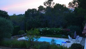 Une piscine entourée d’une végétation luxuriante et d’arbres.