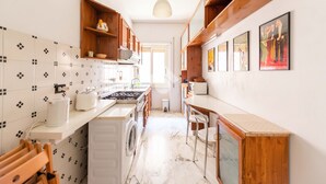 Una cucina ristretta con lavatrice, un fornello e scaffali in legno.