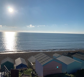Een uitzicht op het strand met een rij strandhuisjes en de oceaan op de achtergrond.