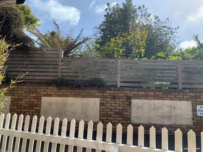 A brick wall with a wooden fence and a sign indicating parking availability.