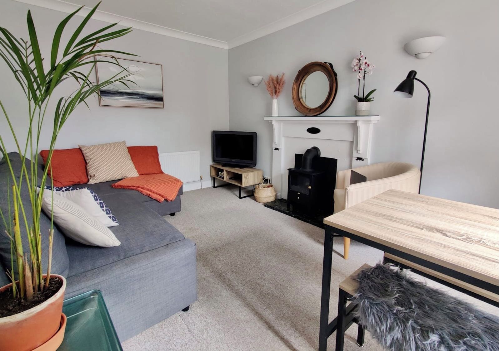 A modern living room with a sofa, TV, fireplace, and a dining table.