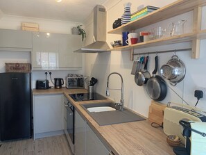 A modern kitchen with a built-in dishwasher, a sink with a stainless steel faucet, and a variety of cookware and utensils on the wall.